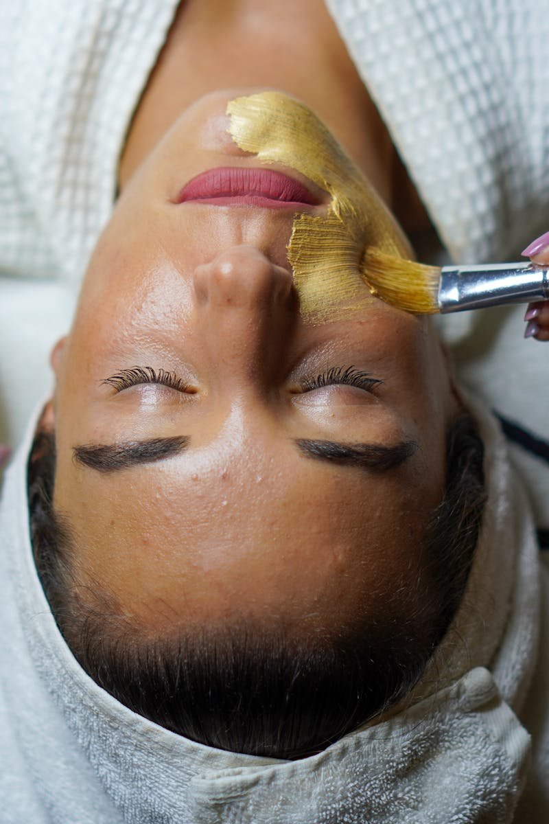 A woman enjoying a gold facial mask for relaxation and skincare at a spa.
